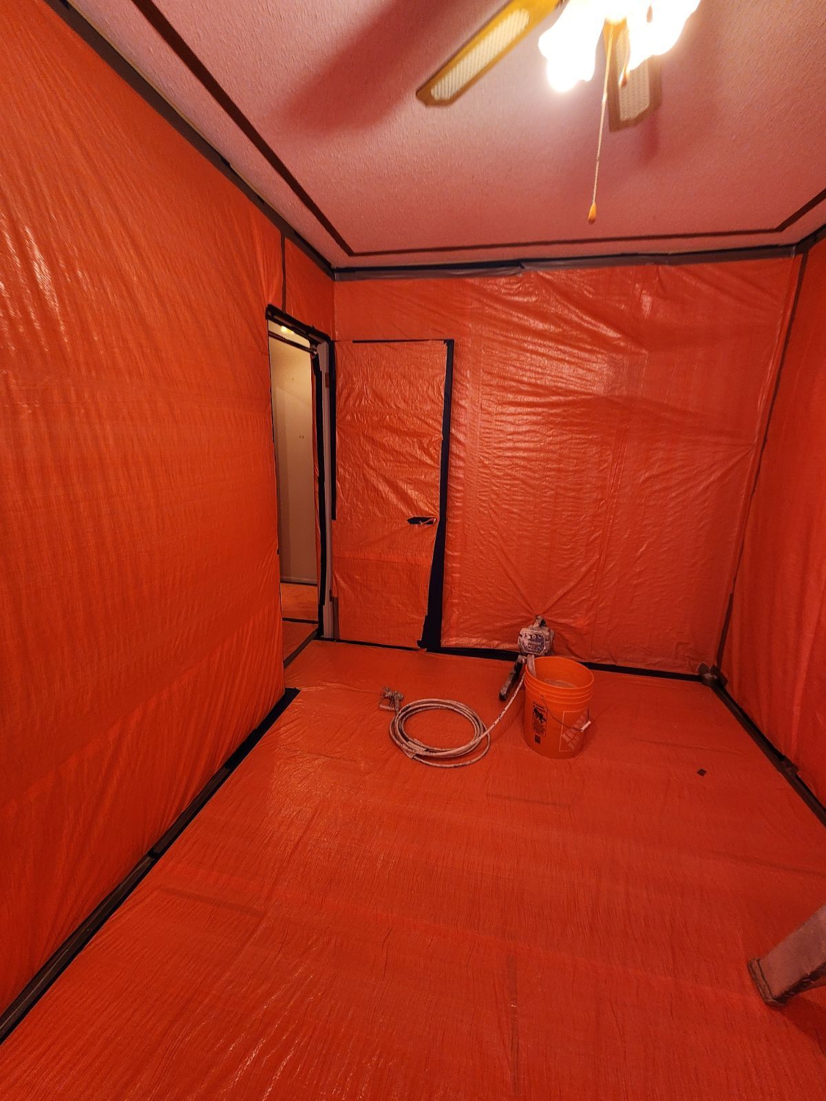 Interior room enclosed in orange containment sheeting for abatement work