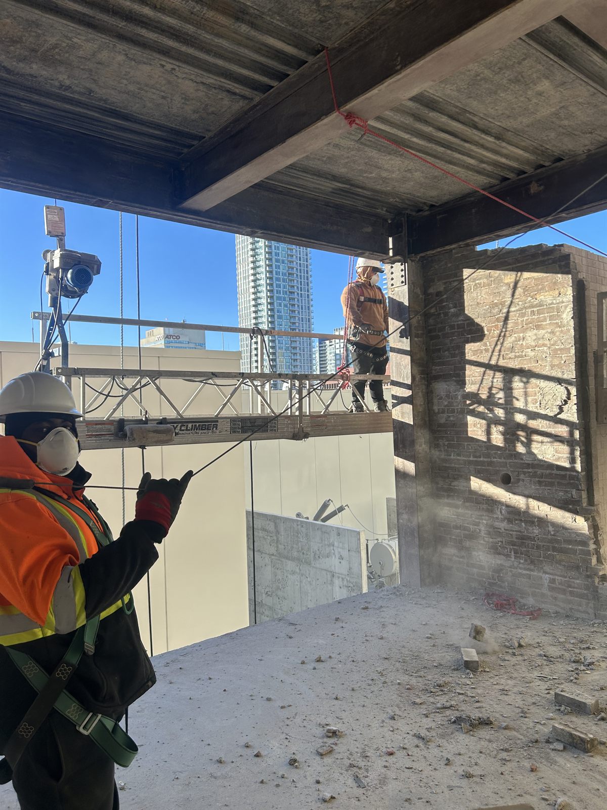 Labbe crew in protective gear working beside a partially demolished brick wall and scaffolding