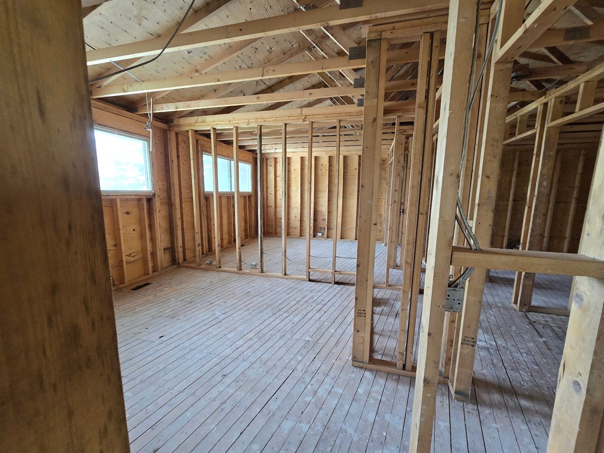 Stripped residential interior with exposed wall studs and ceiling framing
