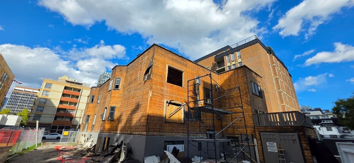 Building exterior with cladding removed, exposed wood sheathing and scaffolding on a Labbe project